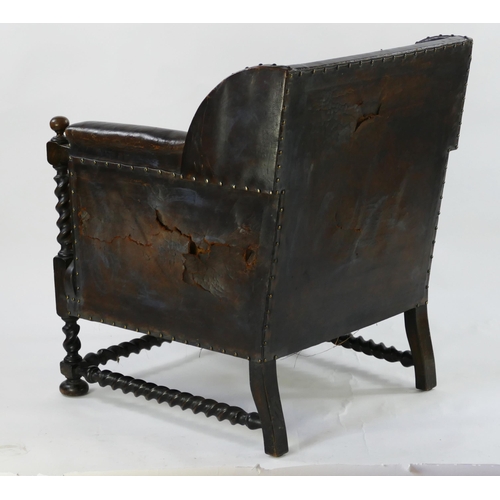 1495 - An Edwardian oak and leather upholstered armchair, with wing back, padded arm rests, loose cushion