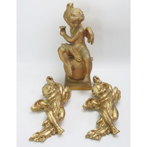 1540 - A gilded statue of a cherub seated on a ball, mounted on a square base. 41cm high, together with two... 