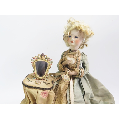 1571 - A continental bisque head doll automaton, of a seated lady at her dressing table holding a hand mirr... 