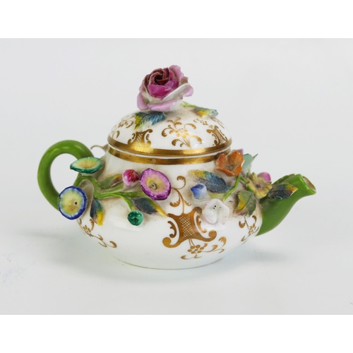 1585 - A German porcelain miniature teapot with floral encrusted decoration, 10cm long.