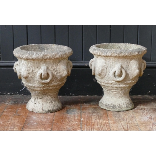 1656 - A pair of reconstituted stone urns of campana form raised on circular bases, 29cm high.