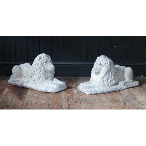 1667 - A pair of reconstituted stone lions couchant, on naturalistic rectangular bases, 71cm long, 34cm hig... 