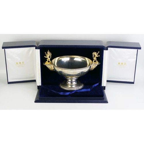 An Elizabeth II  modern parcel-gilt silver commemorative two-handled rose bowl,
by Garrard and Co, London 1990, edition number 25/90, of circular form, gadroon border, on a raised circular foot, with a fluted border, with two silver-gilt rampant lions, one crowned, inscribed 'A Birthday Tribute to Her Majesty Queen Elizabeth The Queen Mother 4th August 1990', diameter handle to handle 35.5cm, with COA, cased, 2058gms, 66.16ozs