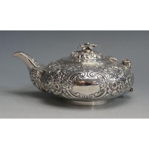 502 - A George IV silver teapot, maker Thomas Baker London, 1823, crested, of circular form with embossed ... 