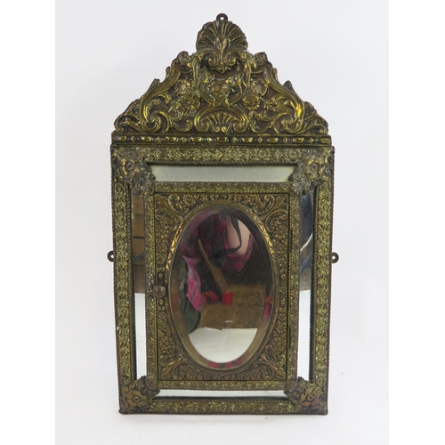 1781 - An early 20th century brass and mirror panelled wall cabinet, of arched outline, the cushioned door ... 