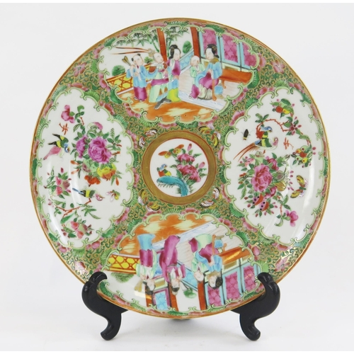 1843 - A Cantonese famille rose plate, decorated with panels depicting figures in interiors.25cm diameter.