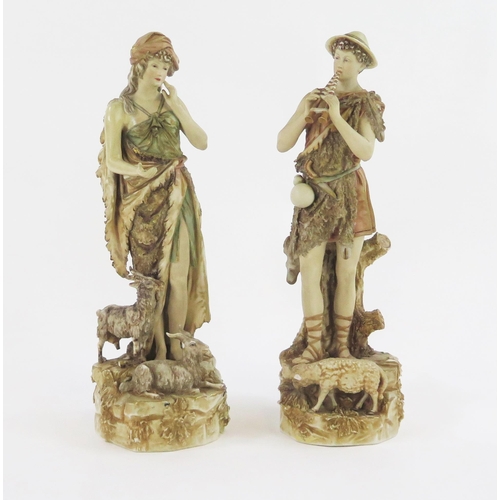 1868 - A pair of Royal Dux style figurines of a shepherd and shepherdess, on naturalistic bases with sheep,... 