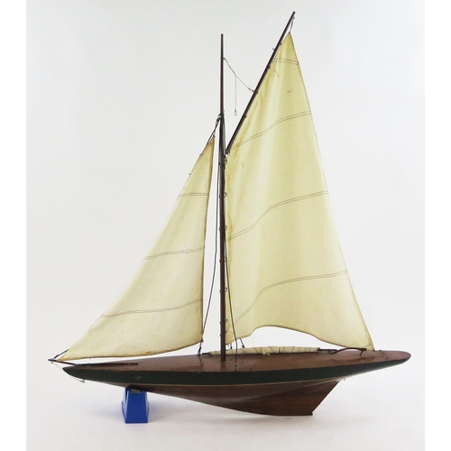 1915 - A pond yacht, with painted mahogany hull, with linen sails, overall length  94cm.