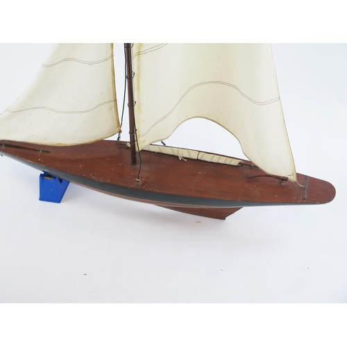 1915 - A pond yacht, with painted mahogany hull, with linen sails, overall length  94cm.