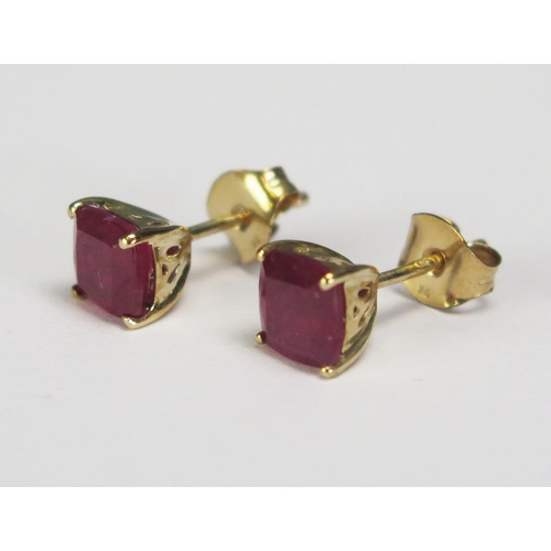 294 - A pair of cushion cut ruby ear studs, approx 2ct, in9ct gold mounts.