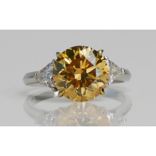 81 - A Yellow Diamond Solitaire Ring in a platinum setting shouldered by white triangular cuts, size J, s... 