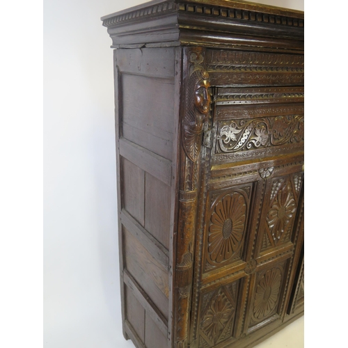 800A - A 17th century carved oak marriage/livery cupboard, with dentil moulded cornice, above a pair of hea... 