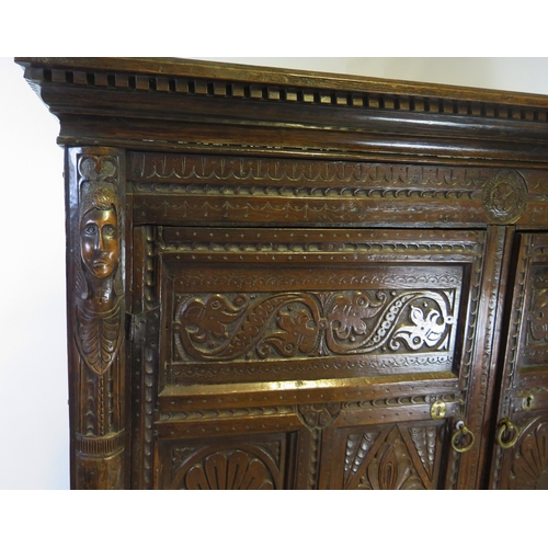 800A - A 17th century carved oak marriage/livery cupboard, with dentil moulded cornice, above a pair of hea... 