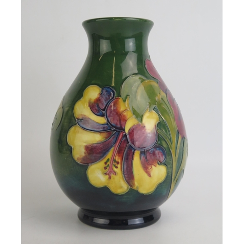 1073 - A Moorcroft pottery vase with Hibiscus pattern decoration, of ovoid form to a green ground, 20cm hig... 