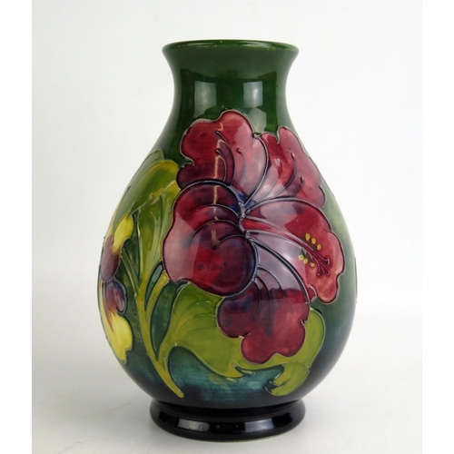 1073 - A Moorcroft pottery vase with Hibiscus pattern decoration, of ovoid form to a green ground, 20cm hig... 