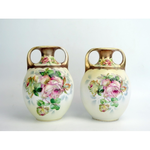 1082 - A pair of German porcelain twin handled vases, with rose pattern decoration, 18cm high.