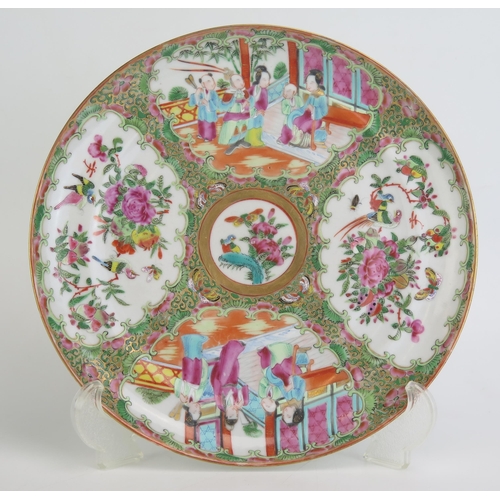 1139 - A Cantonese famille rose plate, decorated with panels depicting figures in interiors.25cm diameter.