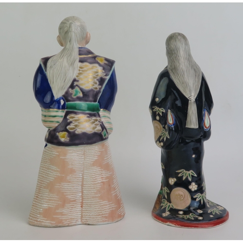 1149 - Two Japanese porcelain figures of a man and woman wearing traditional costumes, 24cm and 26cm high.