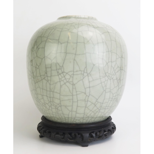 1162 - A Chinese celadon crackle glazed pot, of ovoid form, on a circular wood base, 23cm high, Qing Dynast... 