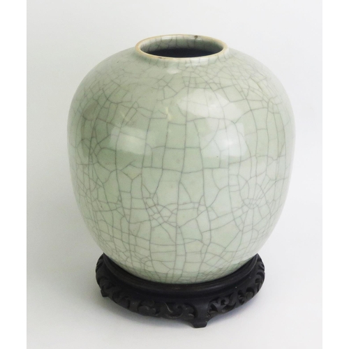 1162 - A Chinese celadon crackle glazed pot, of ovoid form, on a circular wood base, 23cm high, Qing Dynast... 