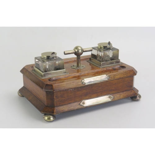 1613 - An Edwardian hardwood and plate mounted ink stand, with two clear glass inkwells, pen troughs, with ... 