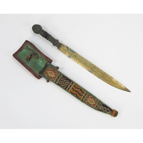 1780 - A Nigerian Yoruba tribe dagger, with 27cm single edged brass blade, turned wood grip, contained in a... 