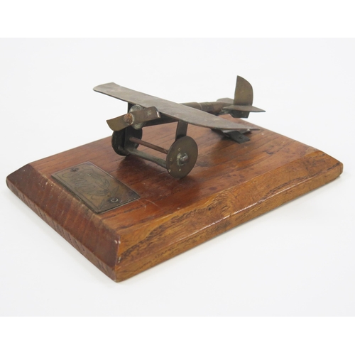 1784 - A World War One trench art model of a monoplane, mounted on a polished oak base, the model 10cm long... 