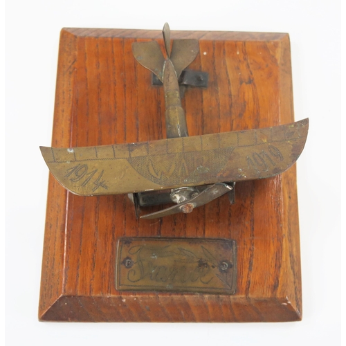 1784 - A World War One trench art model of a monoplane, mounted on a polished oak base, the model 10cm long... 