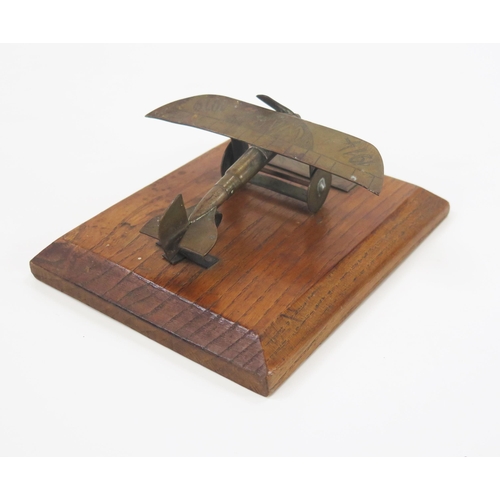 1784 - A World War One trench art model of a monoplane, mounted on a polished oak base, the model 10cm long... 