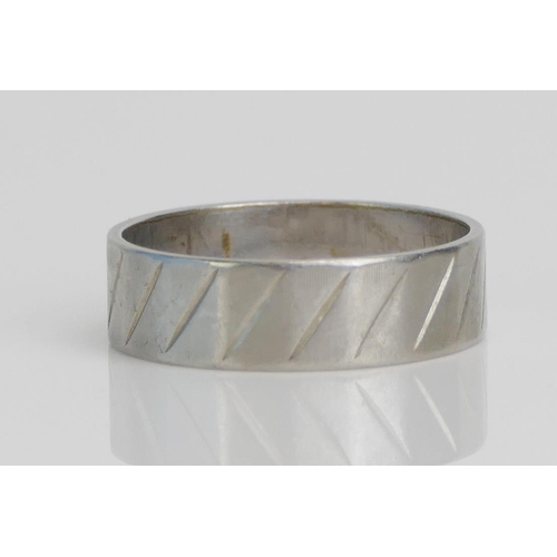 27 - A Platinum Band with faceted decoration, 5.8mm wide, size P, stamped PLAT, 5.39g