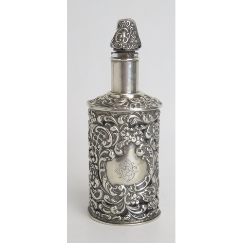 532 - An Edwardian silver cased clear glass bottle and stopper, monogrammed, with pierced foliate and scro... 