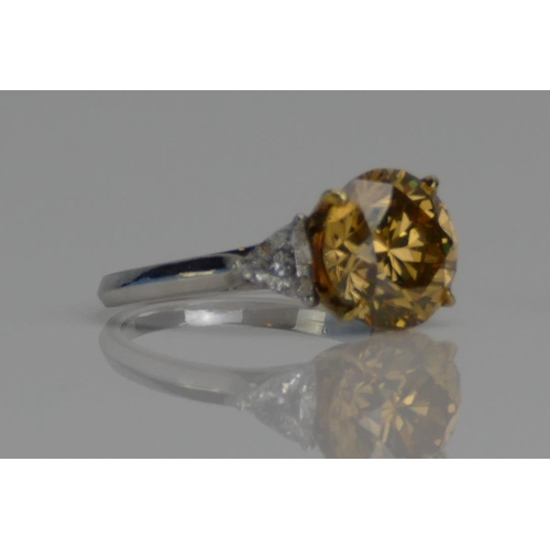 81 - A Yellow Diamond Solitaire Ring in a platinum setting shouldered by white triangular cuts, size J, s... 