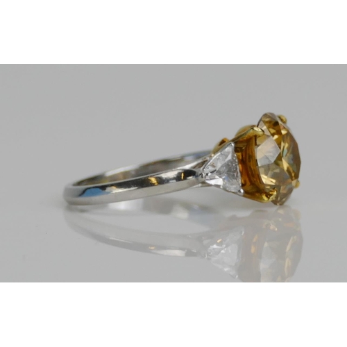 81 - A Yellow Diamond Solitaire Ring in a platinum setting shouldered by white triangular cuts, size J, s... 