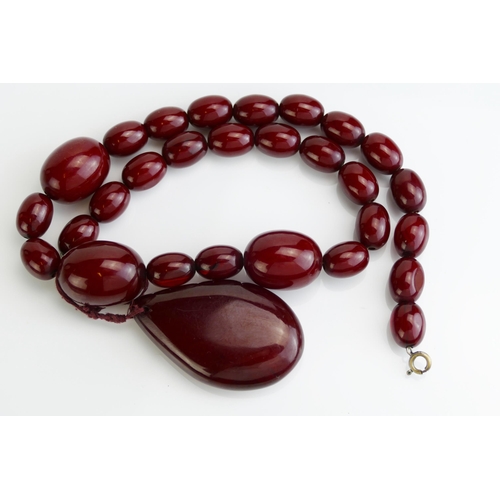 84 - A Faux Red Amber Bead Necklace with pear shaped pendant suspension, largest bead c. 33.6x21.3mm, pen... 