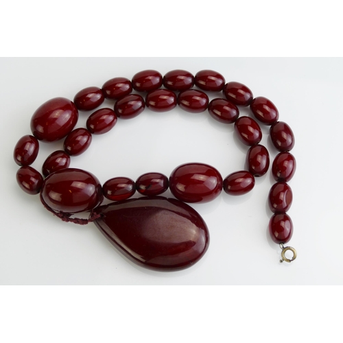 84 - A Faux Red Amber Bead Necklace with pear shaped pendant suspension, largest bead c. 33.6x21.3mm, pen... 