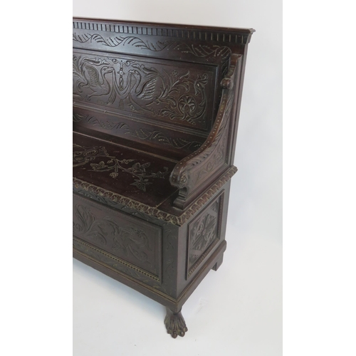 813 - A Carved Oak Settle with hinged lift up seat , the back carved with birds and the whole with foliate... 