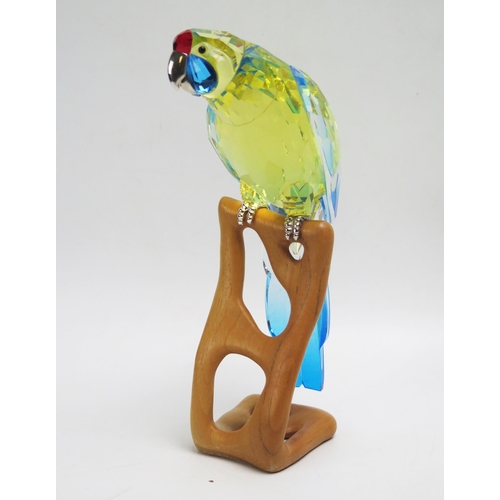 1095 - A Swarovski crystal parrot, mounted on a shaped wood Perch, 22cm high