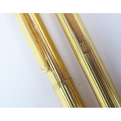 1221 - A Must de Cartier gold plated ball point pen with reeded decoration, together with a similar Cartier... 