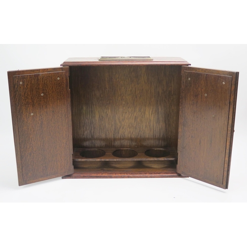 1248 - An oak smokers cabinet, of rectangular outline, the top with plaque 1939-1945, the two panelled cupb... 