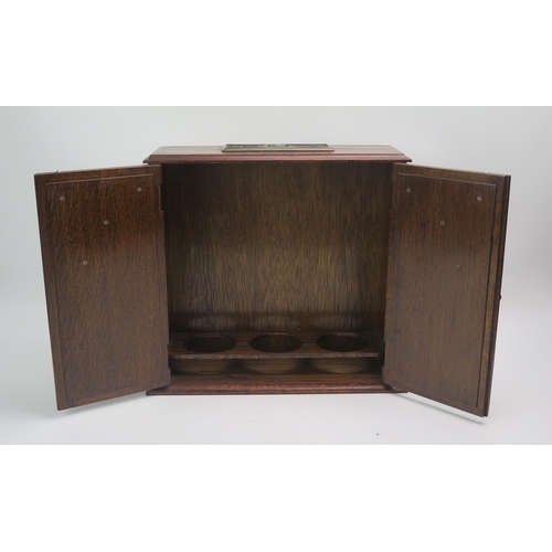 1248 - An oak smokers cabinet, of rectangular outline, the top with plaque 1939-1945, the two panelled cupb... 