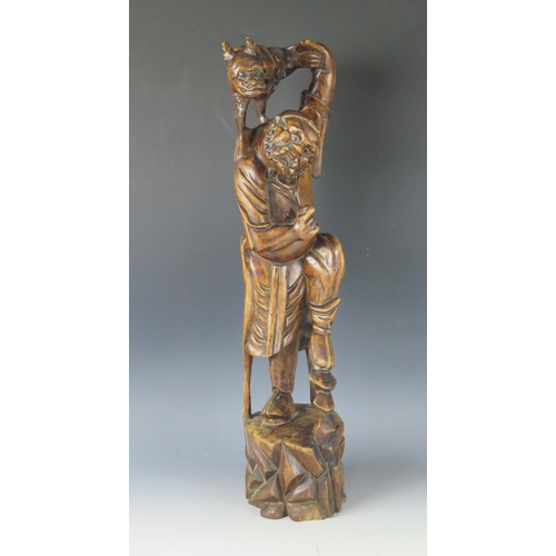 1295 - A Japanese carved root wood okimono of a bearded man holding a mythical beast on his shoulders, on a... 