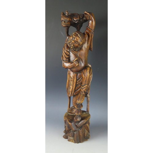 1295 - A Japanese carved root wood okimono of a bearded man holding a mythical beast on his shoulders, on a... 