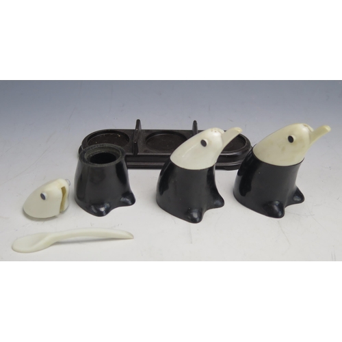 1310 - A vintage Bakelite three piece condiment set in the form of penguins, on an associated Bakelite stan... 