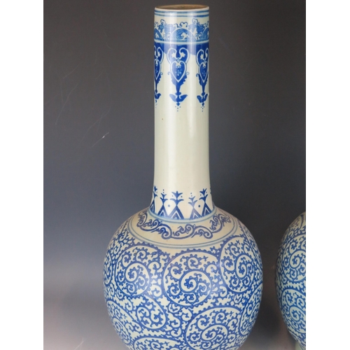 1407 - A pair of large blue and white vases of ovoid form with tall slender necks, having scrolling decorat... 