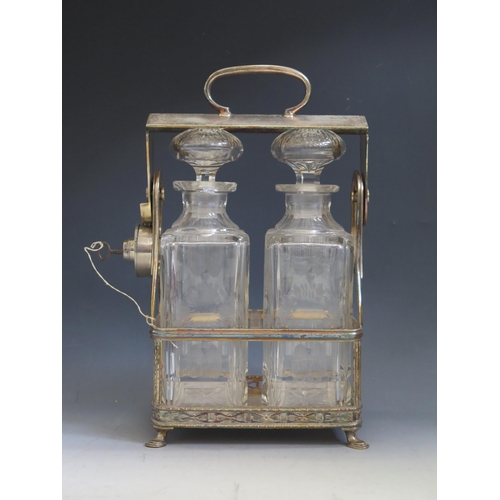 631 - A plated tantalus containing two etched glass decanters and stoppers, the frame with loop carrying h... 