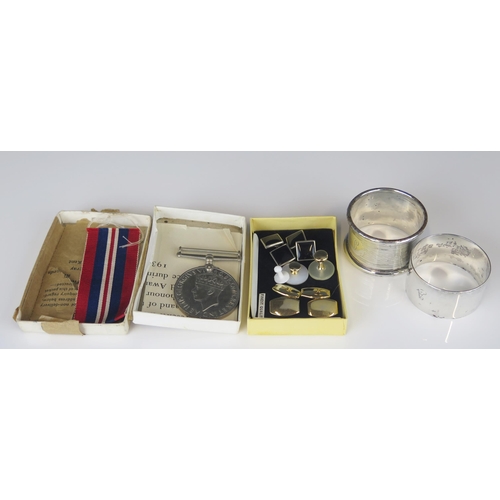 699 - Two silver napkin rings, a World War II War Medal and cufflinks.