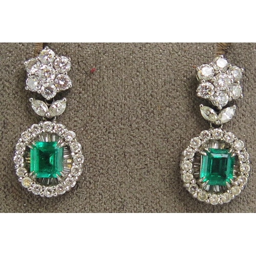 A Pair of 18K White Gold, Emerald and Diamond Pendant Earrings with a top cluster above a suspended twin foliate 'leaf' above the suspended emerald and diamond cluster, c. 5.85x5.2mm principal stone, butterflies stamped 750 18K, 10.7g.

Sold with an insurance certificate describing them as Columbian emeralds weighing 1.42cts and the diamonds 2.48cts and a value of £9000.