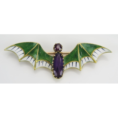 184 - A Suffragette Bat Brooch set with an amethyst and with green and white enamel wings and a further ru... 