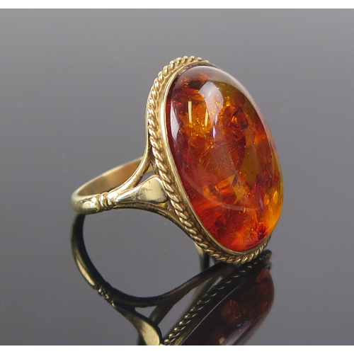 13 - An amber ring in a 9ct yellow gold setting, c. 24.8x12.4mm specimen, size S.5, 6.51g. Boxed