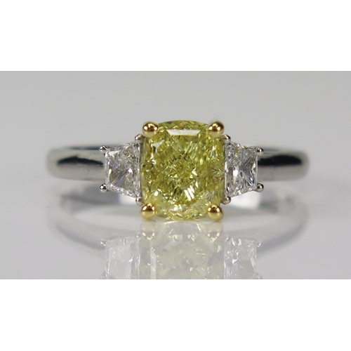 A Cartier trilogy ring with a central 1.8ct fancy yellow diamond flanked by trapezoid cut diamonds and in a .950 platinum setting , size R, full Cartier marks (serial no. CYJ184). Sold together with a Cartier suede wallet.

GIA report stating the cushion modified brilliant cut fancy yellow stone is natural and with even colour distribution and VVS2 clarity.